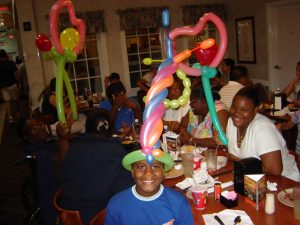 More happy kids with balloons at a restaurant.